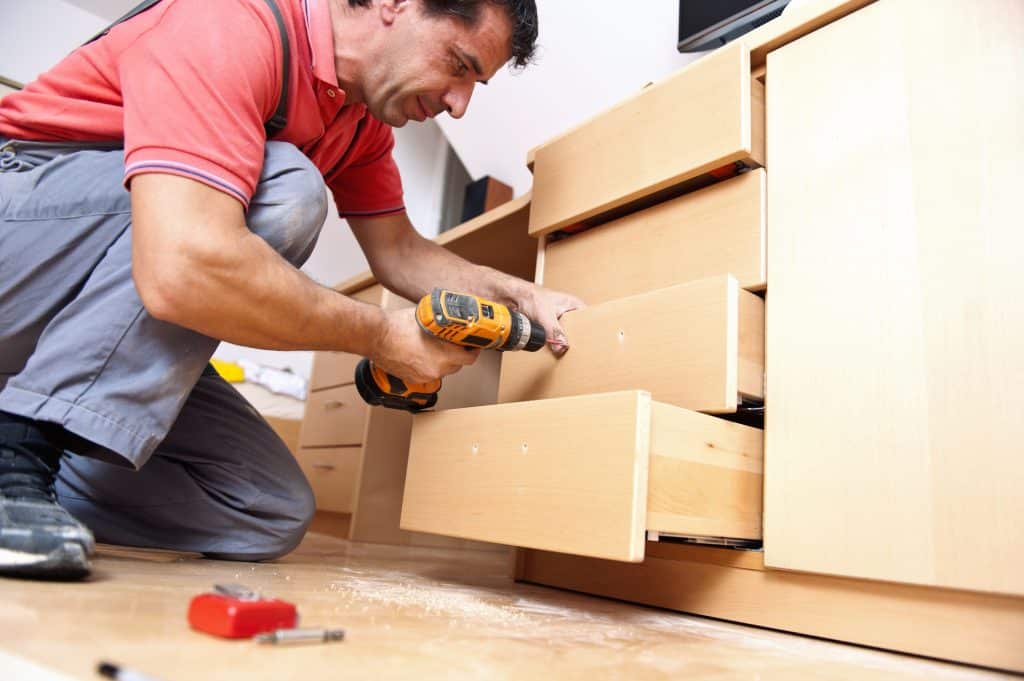 man installing drawer pulls on kitchen cabinets